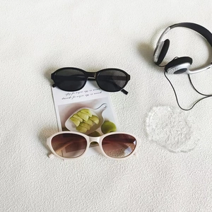 Flat lay detail of oval sunglasses in black and beige with high-quality resin lenses