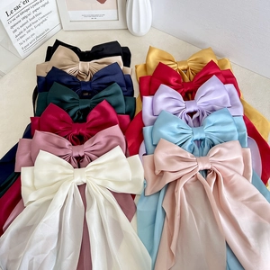 Elegant multi-color satin bow hair clips with long ribbons displayed on a minimalist desk