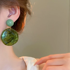 Detail of vintage emerald green marbled resin earrings with gold metallic accents