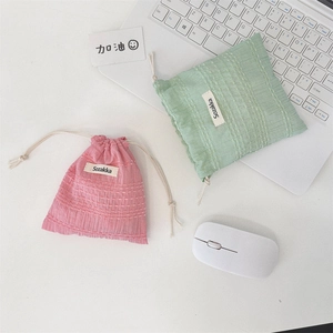 Pink and mint green drawstring organizer bags with waffle texture on an office desk