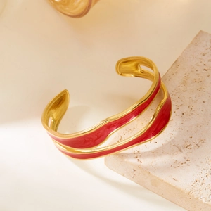 Detail view of double-layered wave gold bangle with red enamel finish on stone