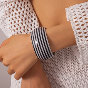 Macro di un ampio bracciale rigido in acrilico a righe bianche e nere sul polso