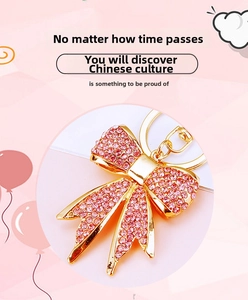 Close-up of pink rhinestone bow keychain with gold lobster clasp and sparkling crystals