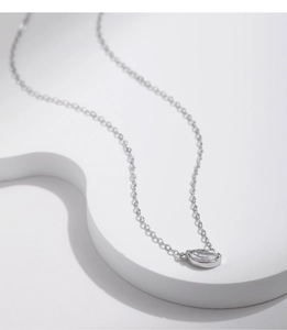 Macro shot of silver S925 necklace with a sparkling oval zircon pendant on a white pedestal