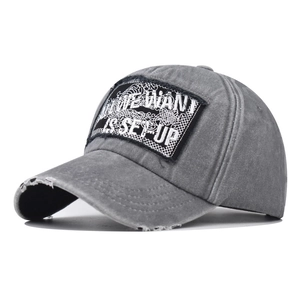Gros plan d'une casquette en coton gris délavé avec écusson brodé et détails usés