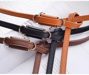 Detailed view of thin PU leather belts in brown and black with gold buckles