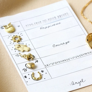 Close-up of golden symbolic pendants set including owl elephant and hamsa hand charms