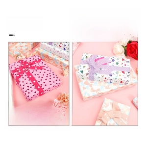 Detail of Valentine's gift wrapping paper with gold heart patterns and ribbon bows