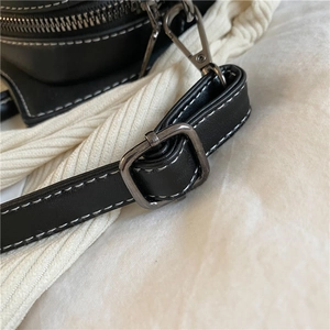 Detailansicht des schwarzen PU Leder Handtaschenriemens mit kontrastierenden weißen Nähten und Metallschnalle.