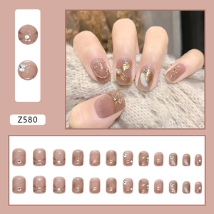 Faux ongles nude translucides avec feuille d'or, perles et accents pailletés