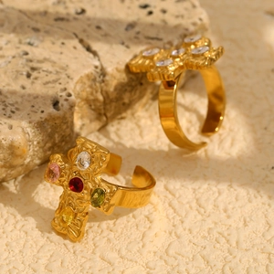 Macro view of adjustable 18K gold-plated cross rings with colorful crystals on stone