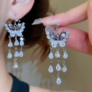 Detail of silver butterfly tassel earrings with purple zircons worn by a model