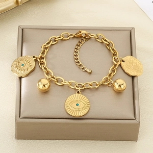 Detail of gold evil eye and hamsa hand charms on a chunky stainless steel bracelet