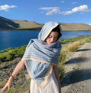 Blue and beige houndstooth scarf draped over a model's head and shoulders outdoors