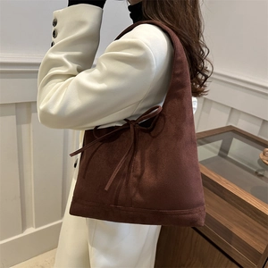 Brown suede tote bag with bow detail worn by model in a white suit for office look