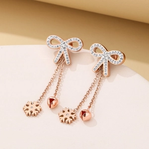 Detail of rose gold tassel earrings featuring rhinestone bows and snowflake charms