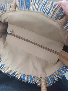 Detailed interior of round straw bag showing beige lining and functional zipper pocket