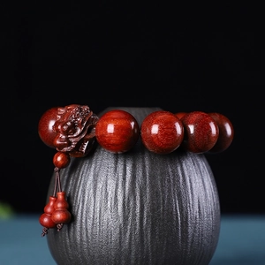 Détail macro de perles en santal d'Afrique avec breloque tête de dragon sculptée