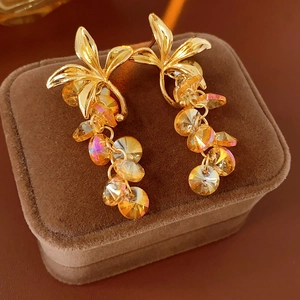 Macro detail of vintage gold flower earrings with amber crystal tassels on brown suede