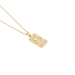Detailed macro of a gold rectangular pendant featuring a heart lock and key with zircons
