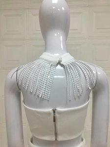 Vista posteriore del top bianco con frange lunghe e borchie metalliche argentate