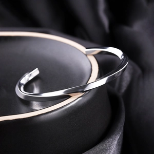 Macro shot of polished silver Mobius twist cuff bracelet on elegant black silk background