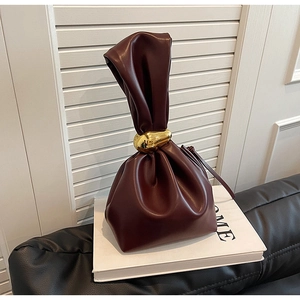 Close-up of burgundy leather bucket bag with knotted handle and gold metallic buckle
