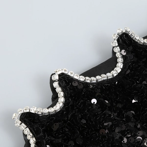 Détail des paillettes noires scintillantes et bordure en strass argentés de la robe