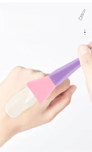 Detail view of the soft silicone face mask applicator with pink brush head and purple handle