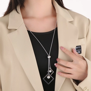 Close-up of a silver geometric square and bead pendant necklace worn with a blazer