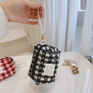 Detail of tweed vanity bags with pearl handles and decorative bows in white and black