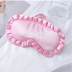 Detail der rosa Seiden-Schlafmaske mit Rüschenrand und Gummiband auf Satin
