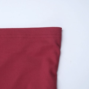 Gros plan de couture double aiguille sur robe moulante bordeaux à épaules dénudées