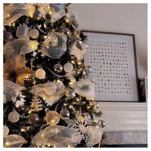 Close-up of silver Christmas mesh ribbon and white snowflake ornaments on a lit Xmas tree