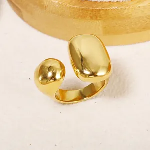 Polished gold stainless steel open ring with asymmetric ball and oval ends in minimalist style