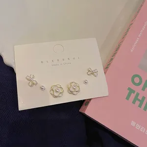 Three-pair earring set featuring bows, camellia flowers, and pearls on display card
