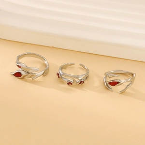 Detailed shot of three gothic silver rings set with red gemstones on warm background