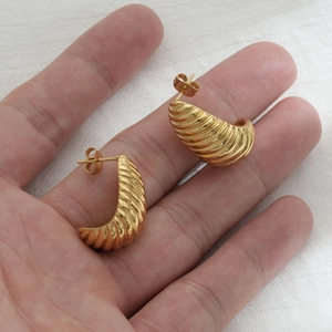 Golden retro croissant twisted stud earrings in stainless steel shown on hand
