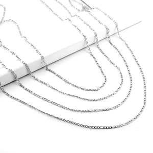 Detail view of silver Figaro link necklaces in various lengths on a white stand