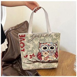 Detail of woven canvas tote bag featuring a colorful owl print and embroidery texture
