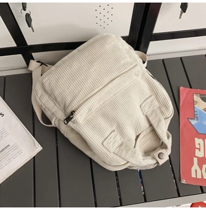 Detailansicht des beigefarbenen Cord-Rucksacks mit Reißverschluss auf einer Bank