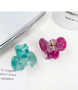 Close-up of mint green and magenta marble textured acetate hair claws on a white tray