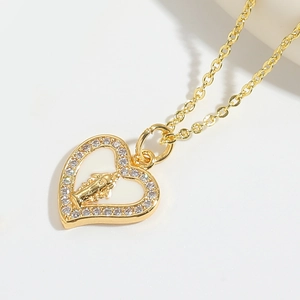 Detail of a golden heart pendant featuring a religious figure and white crystals