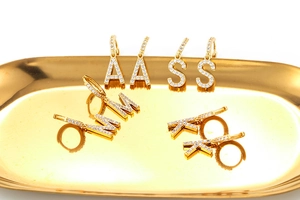 Detail of gold letter earrings A S M K with sparkling pavé zircons on metal tray