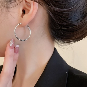 Gros plan d'une boucle d'oreille créole argentée avec strass portée par un mannequin