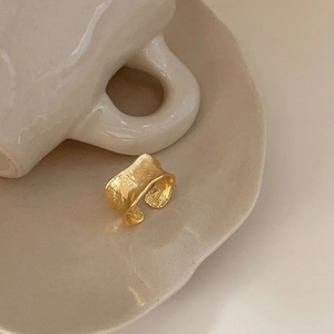 Macro shot of gold-plated open ring with a hammered hammered metal texture on ceramic tray