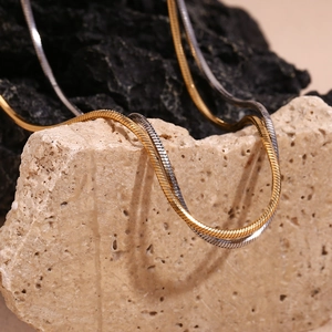 Detailed view of two-tone gold and silver snake chain necklaces on natural stones