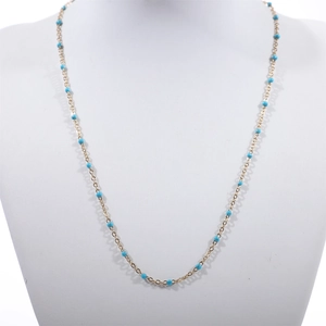 Golden bead chain necklace with sky blue turquoise accents on a jewelry display stand