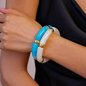 Bracelets en résine acrylique bleu ciel et blanc nacré avec perles dorées portés au poignet