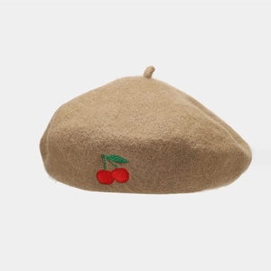 Detailed close-up of cherry embroidery on a warm khaki wool blend beret hat